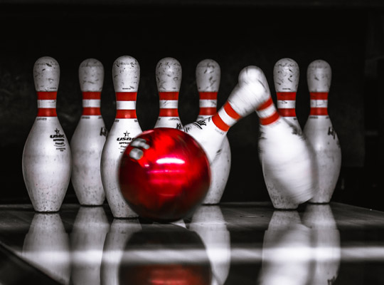 closeup of red bowling ball striking pins