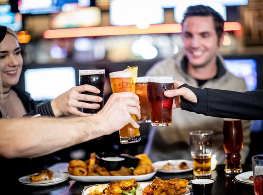 group of people having beer and food at a bowling alley