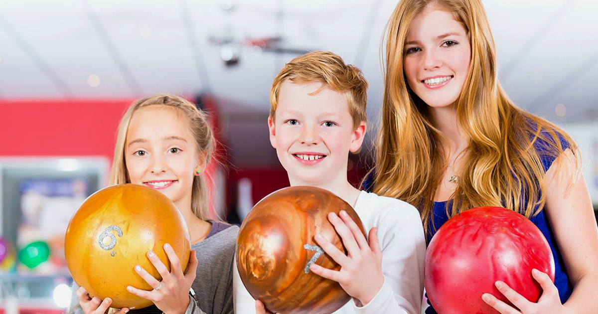 2 kids and an adult holding bowling balls